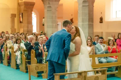 The couple’s first kiss at the top of the aisle with the full congregation standing and applauding behind them