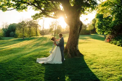 Bride and groom at golden hour under ancient oak tree, Irish estate