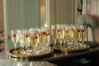 Tray of champagne flutes garnished with raspberries on a gold tray