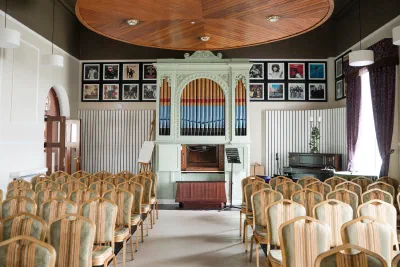 Orlagh House ceremony room set with chairs facing a pipe organ beneath a domed timber ceiling