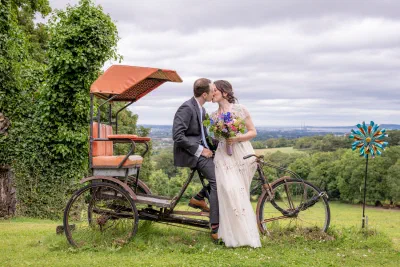 Bride and groom kissing beside a vintage rickshaw bicycle in the grounds at Orlagh House