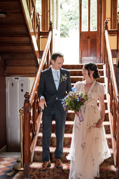 Bride and groom coming down the staircase at Orlagh House together, smiling at each other before the ceremony