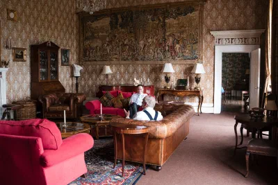 Wedding guests relaxing on leather sofas in the tapestry-hung drawing room at Orlagh House