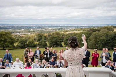 Bride raising a glass to guests seated on the lawn at Orlagh House, with the Dublin skyline beyond