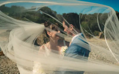 Bride and Groom captured under a windswept veil on Seafield Resort beach, wedding photography and videography by Duffymog Studios