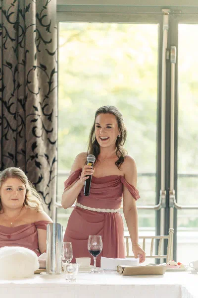 Bridesmaid in a dusty rose dress giving a speech at the top table