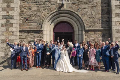 Wedding guests gathered under the arched stone doorway of St Michael’s Church in Gorey, arms in the air, the couple in the middle