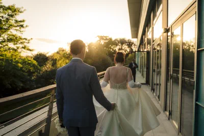 Bride and groom walking back towards the hotel along the terrace into the low evening sun
