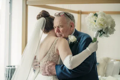 Bride’s father holding her and crying, the bride laughing with her arms around him