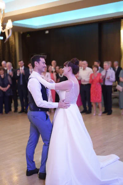 Bride and groom during their first dance, guests circled around the floor