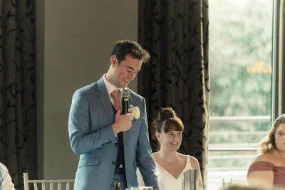 Groom giving his speech beside the bride, the room laughing